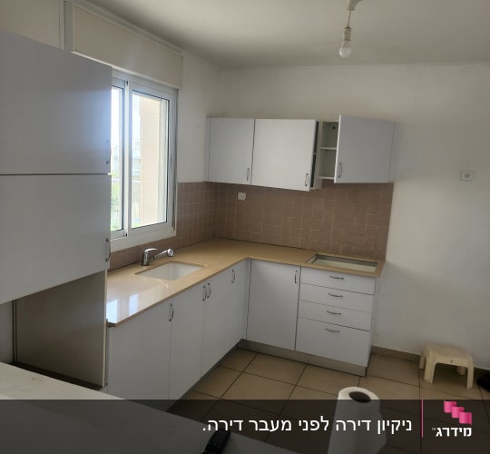 מטבח נקי עם ארונות לבנים ונייר מגבת על השיש